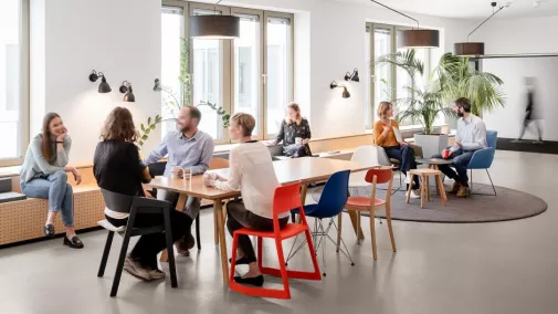 Foto von Mitarbeitenden, die in einem Meetingraum sitzen und sich unterhalten